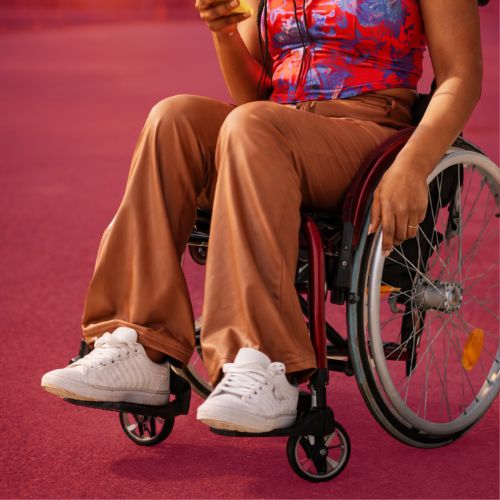 Wheelchair user seated outdoors using a mobile phone independently